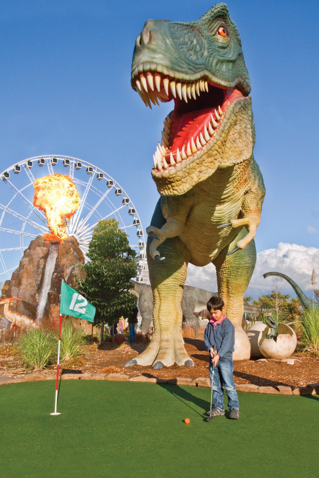 Small child putting under menacing Triceratops at Dino Golf