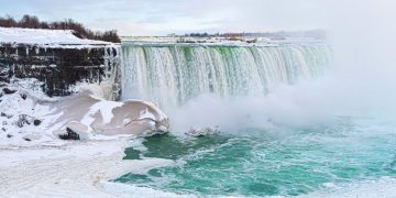 Frozen Niagara Falls in winter, vapour steam, snow in lake