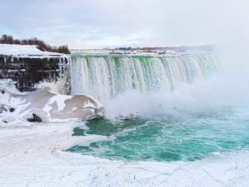 Frozen Niagara Falls in winter, vapour steam, snow in lake