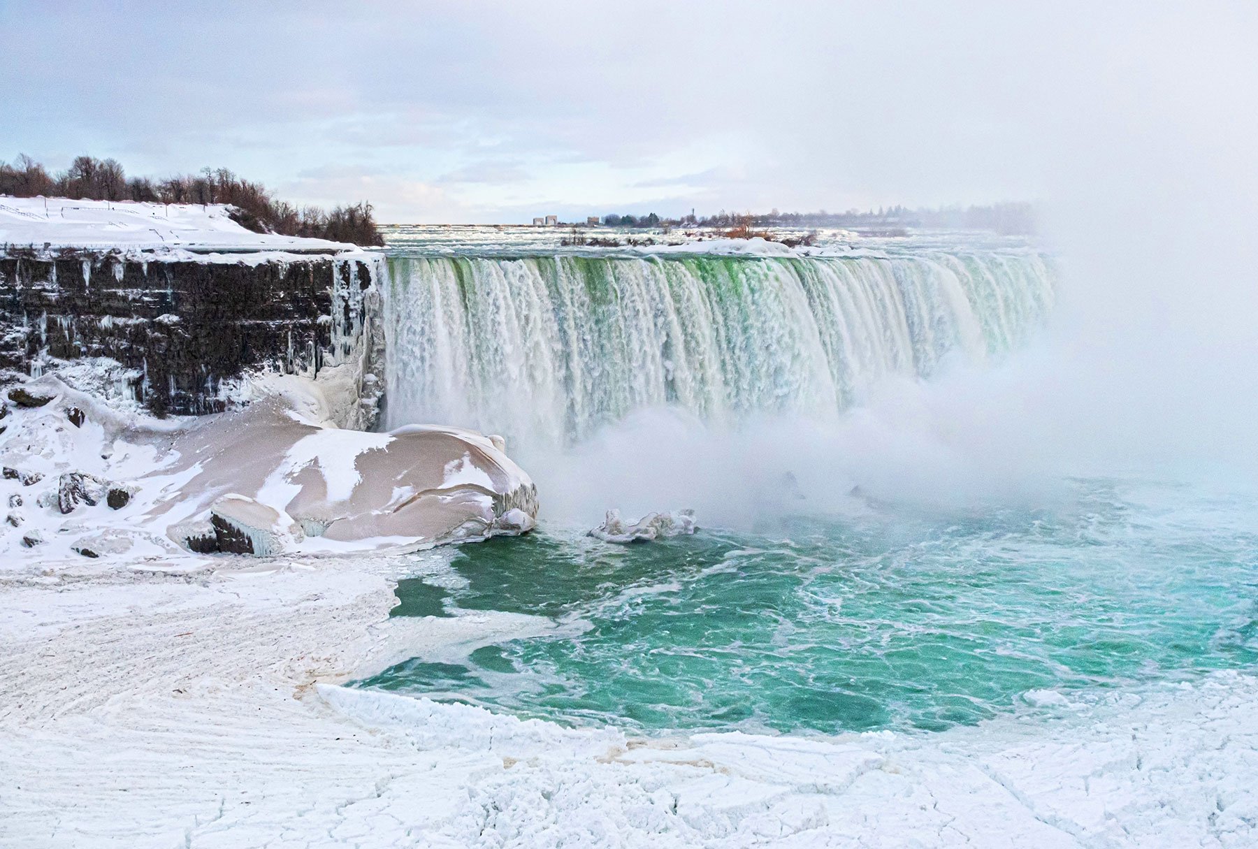 Frozen Niagara Falls in winter, vapour steam, snow in lake