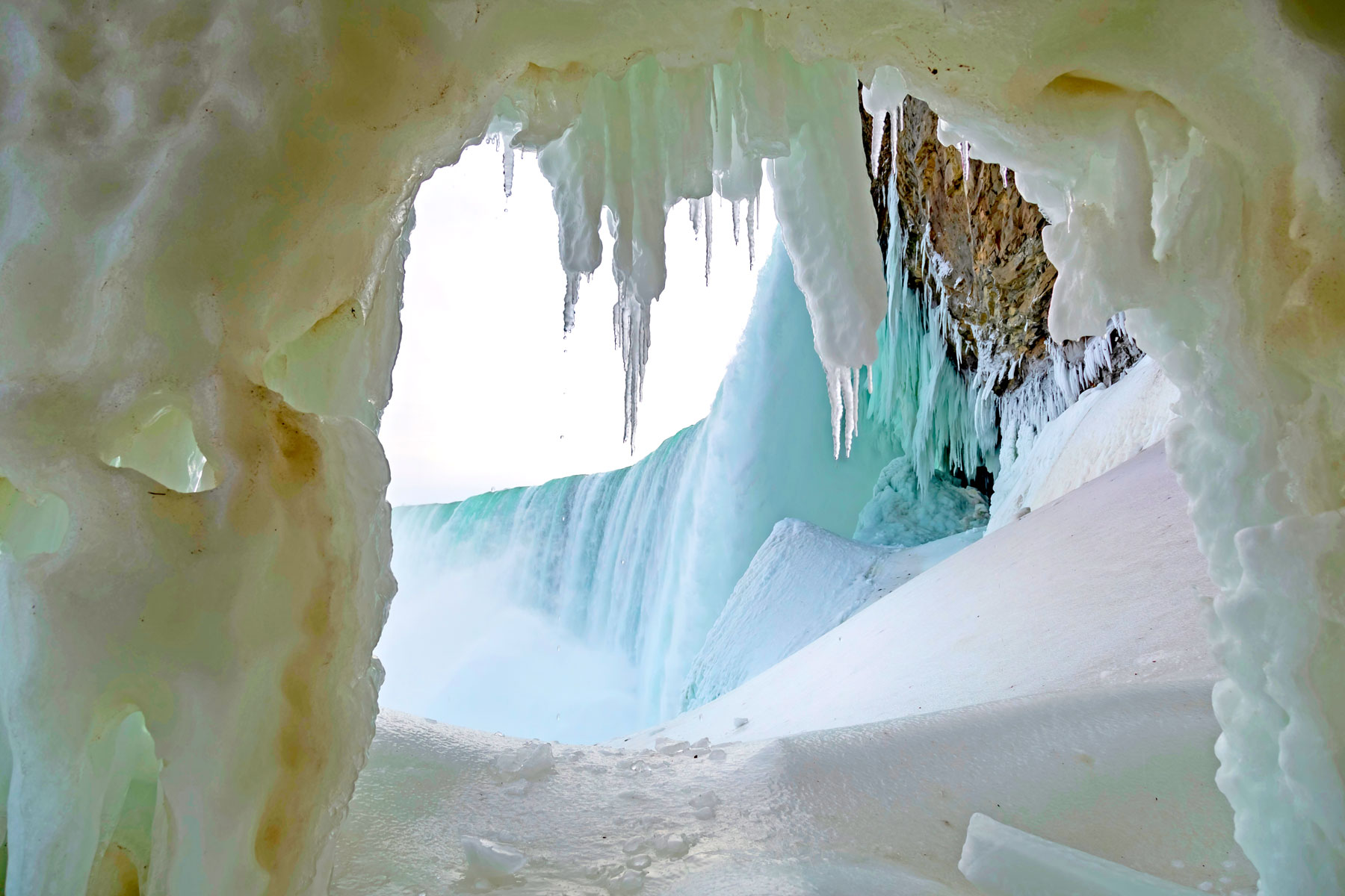 Looking through the ice cave behind Ontario's Niagara Falls as vapor rises over melting icicles