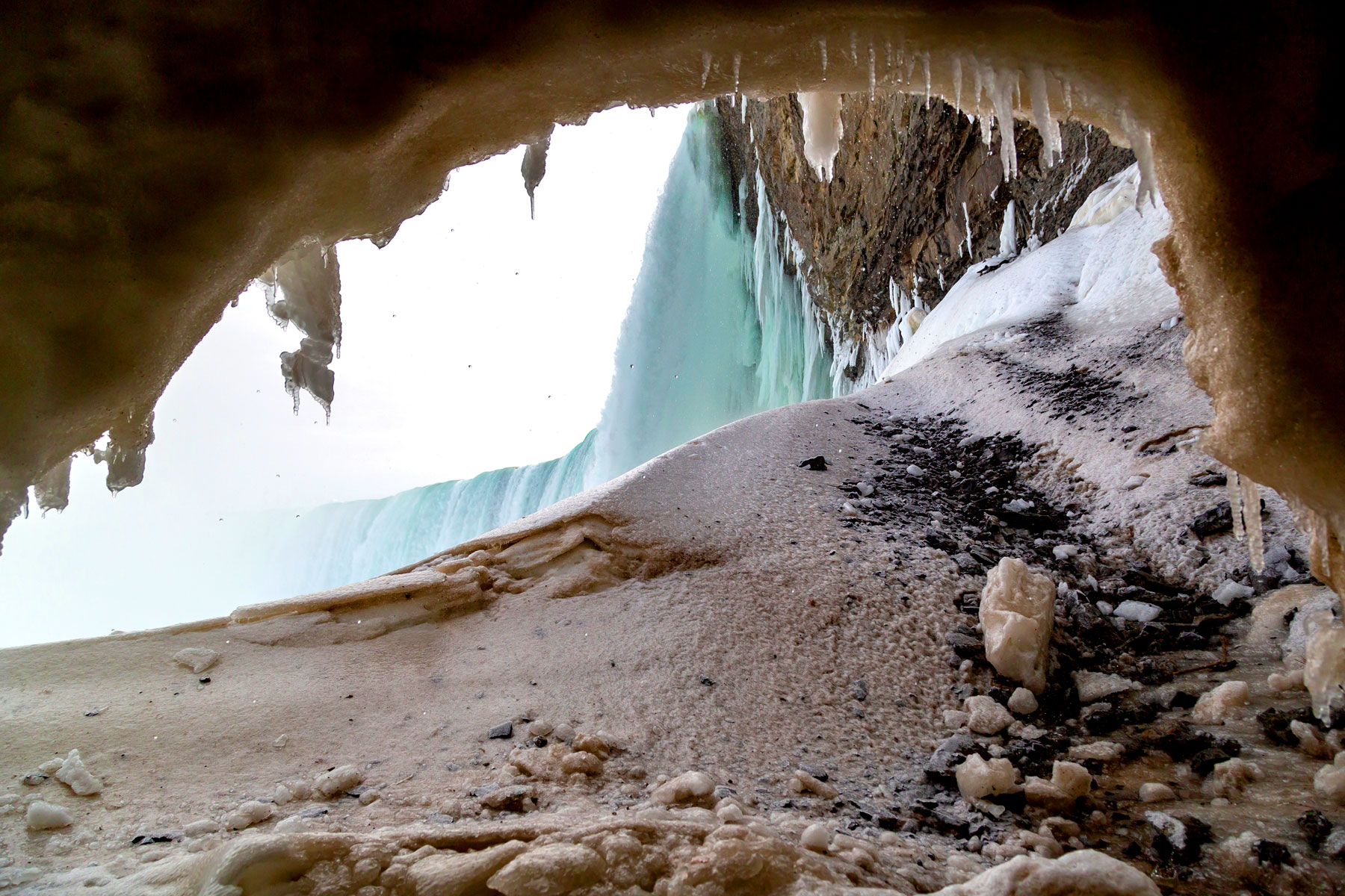 Looking through the ice cave behind Ontario's Niagara Falls as vapor rises over melting icicles