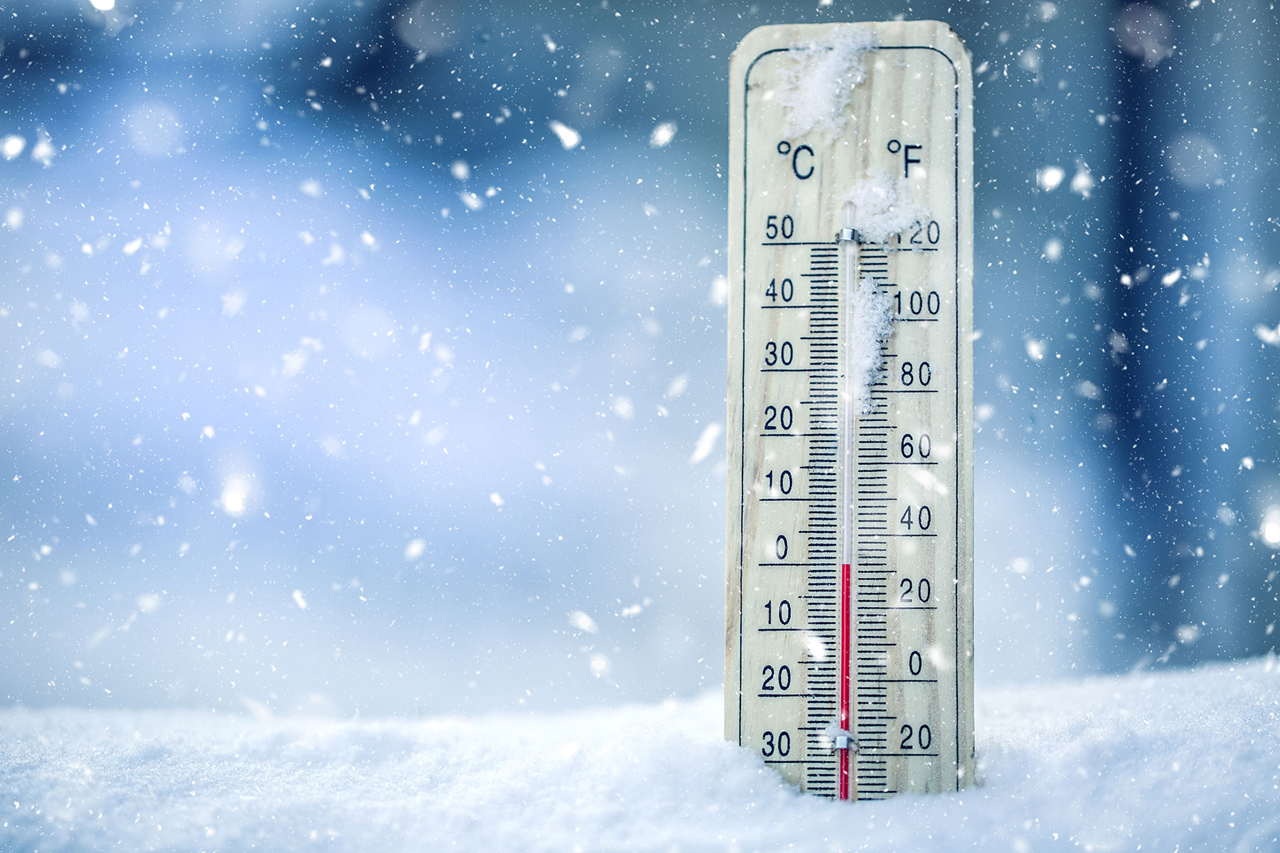 Thermometer on snow shows low temperatures - zero. Low temperatures in degrees Celsius and fahrenheit. Cold winter weather - zero celsius thirty two farenheit