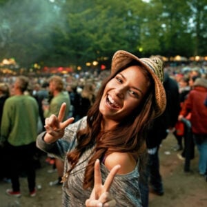 Its all about the vibe. A pretty young woman showing a peace sign at an outdoor music festival.