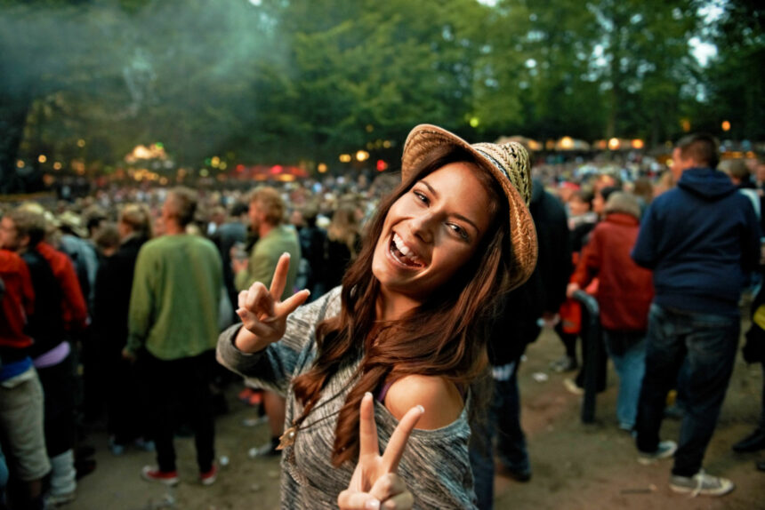 Its all about the vibe. A pretty young woman showing a peace sign at an outdoor music festival.