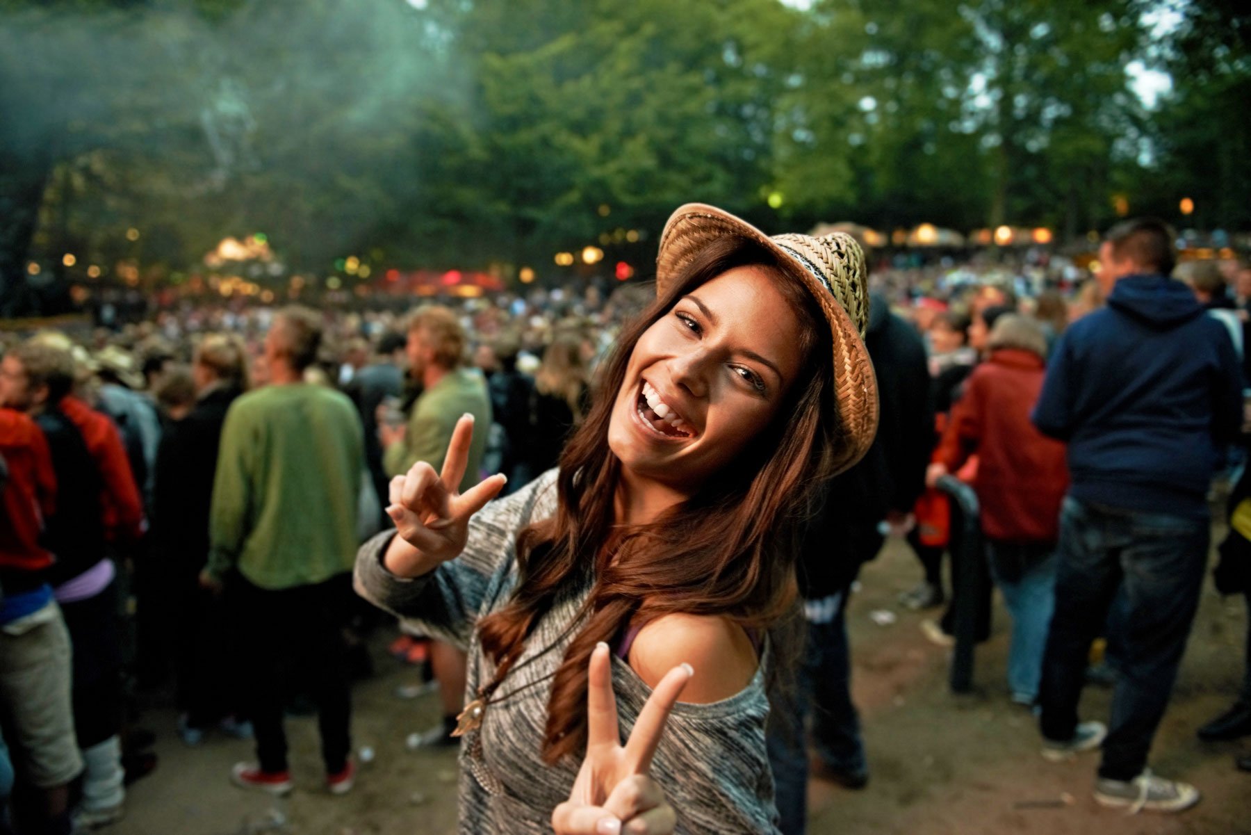 Its all about the vibe. A pretty young woman showing a peace sign at an outdoor music festival.