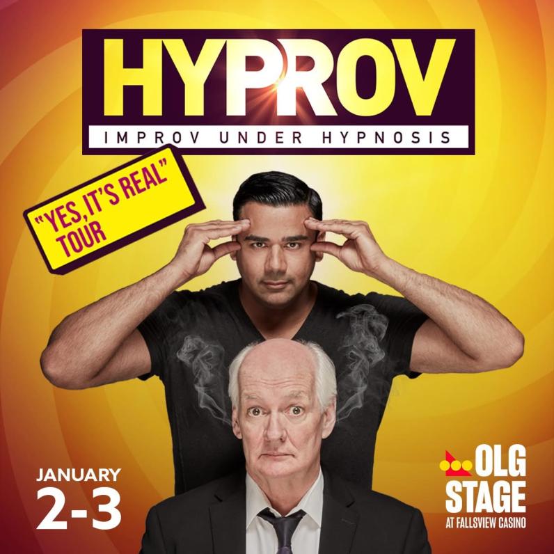 Asad Mecci stands above Colin Mochrie with his fingers on his own temples