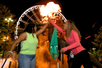 Dino Adventure Golf Clifton Hill at night two ladies high fiving with volcano blasting flames