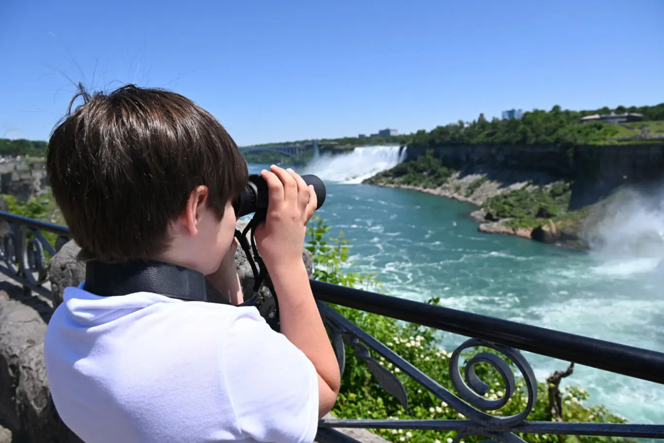 Young man with binoculars looking at Niagara Falls
