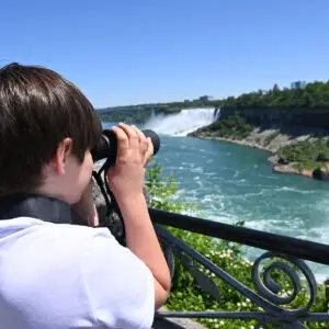 Young man with binoculars looking at Niagara Falls