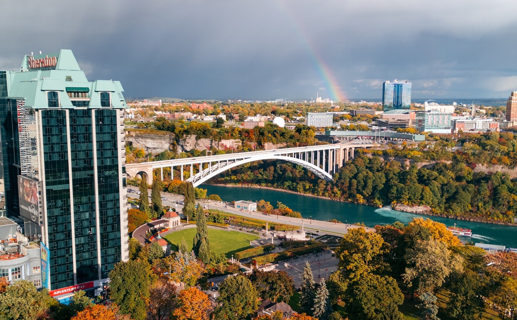 a view of the rainbow bridge on a fall day with a rainbow in the horizon