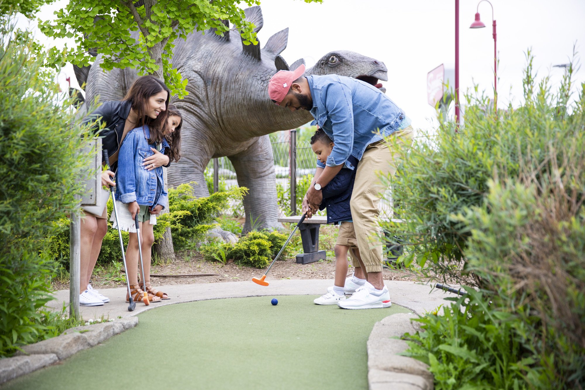 Family putting in front of Dino Adventure Golf volcano in the daytime