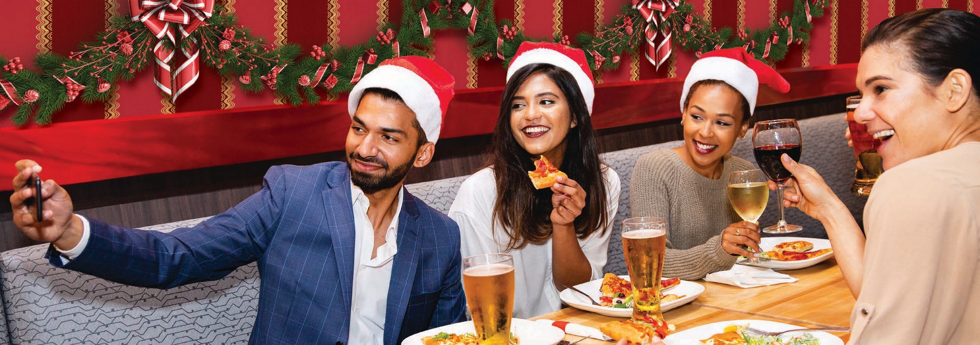 Coworkers in Santa Hats eating at Boston Pizza and taking a photo