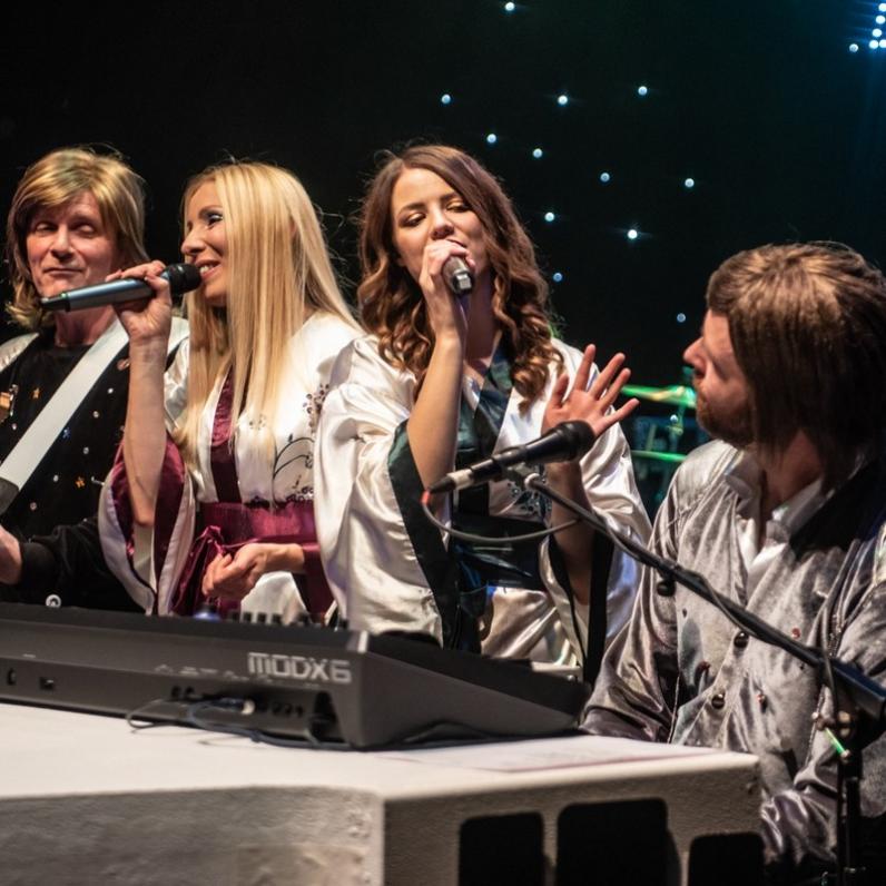 All 4 band members of Abba sitting at the piano
