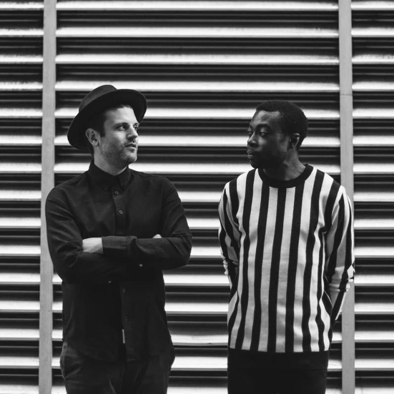 Duo standing in front of a horizontal stripe backdrop