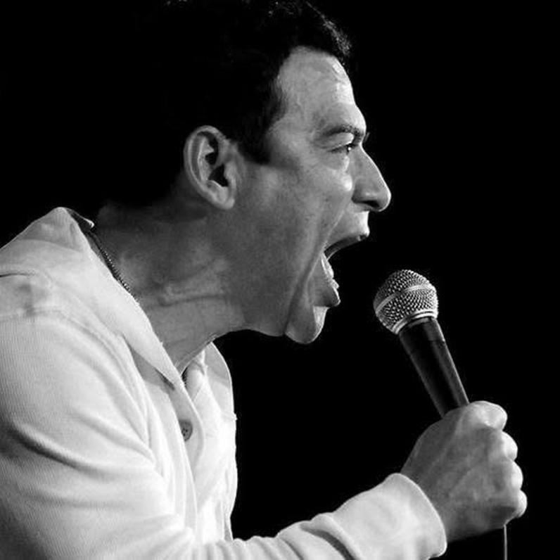 Carlos Mencia talking into a microphone