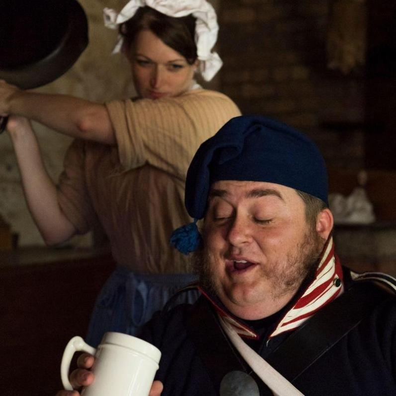 Woman about to hit a man in the head with a cast iron pan