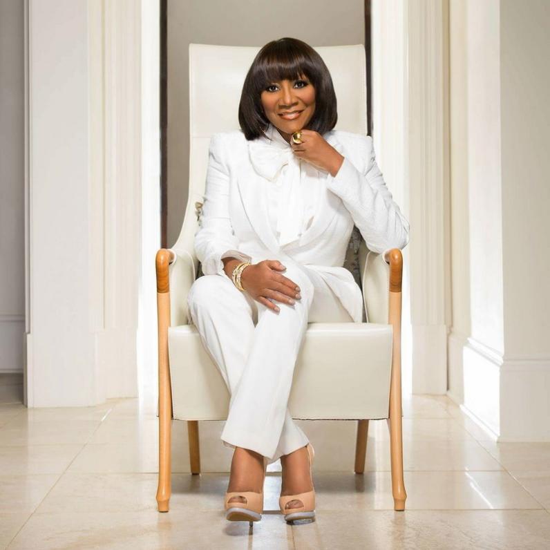 Patti Labelle sitting on a chair dressed in white