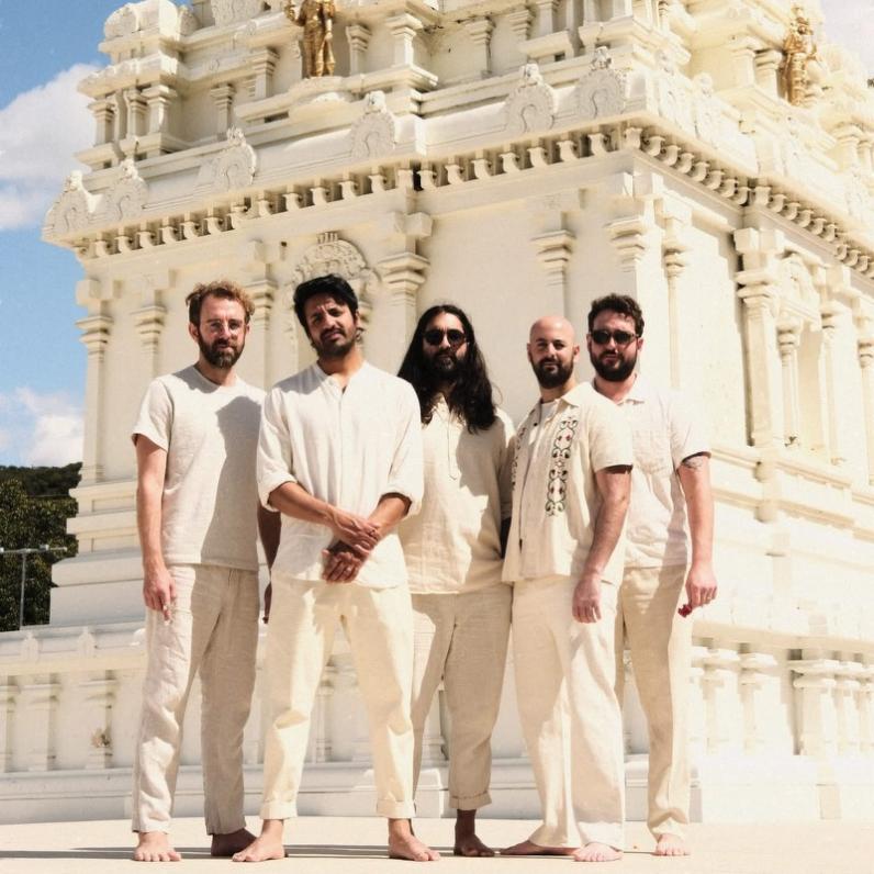 5 men stand barefoot in front of a landmark