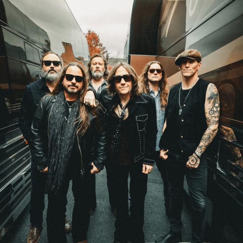 Bandmembers taking a photo between two tour buses
