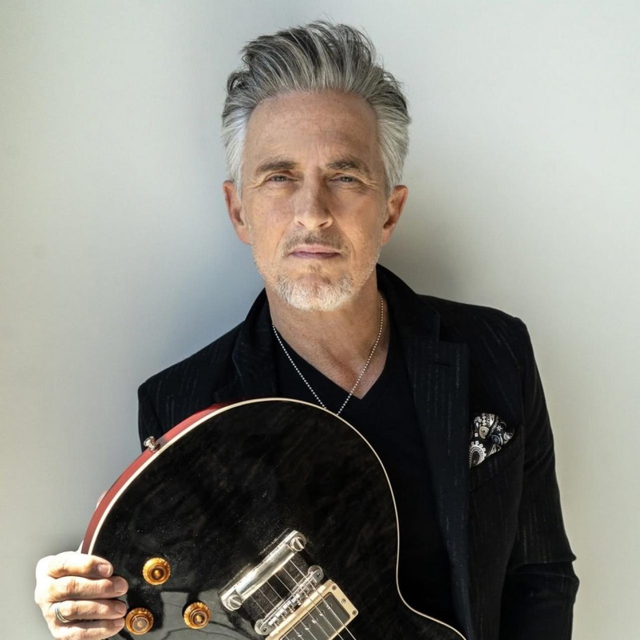 Colin James holding a guitar