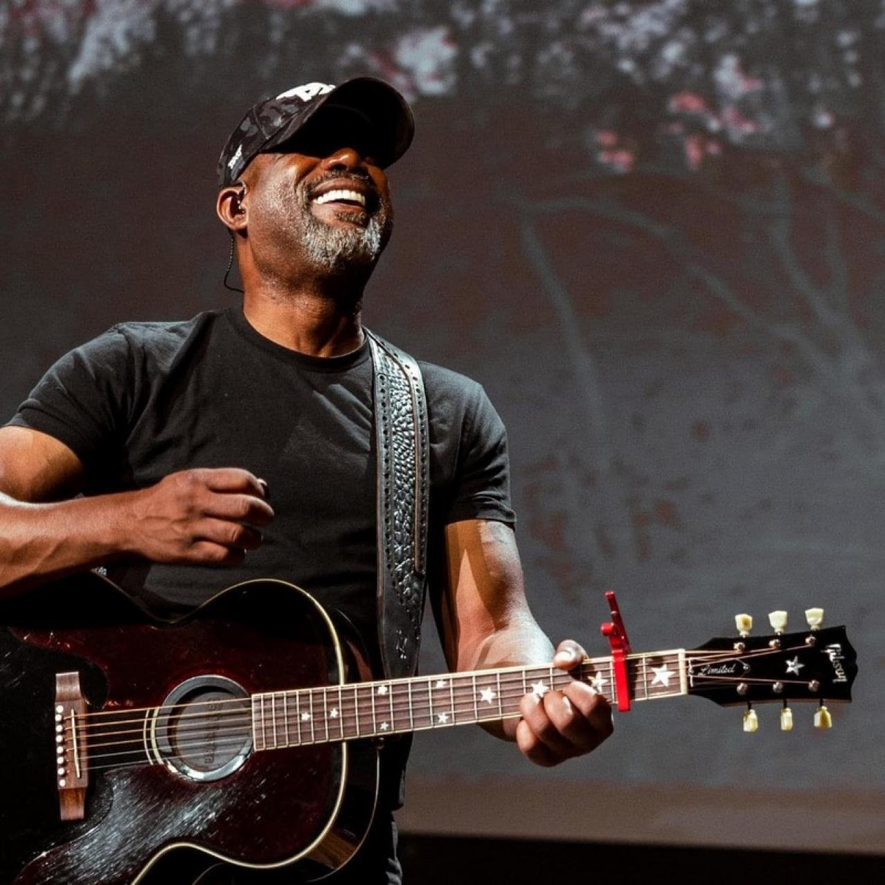 Picture of Darius playing guitar wearing a black baseball hat