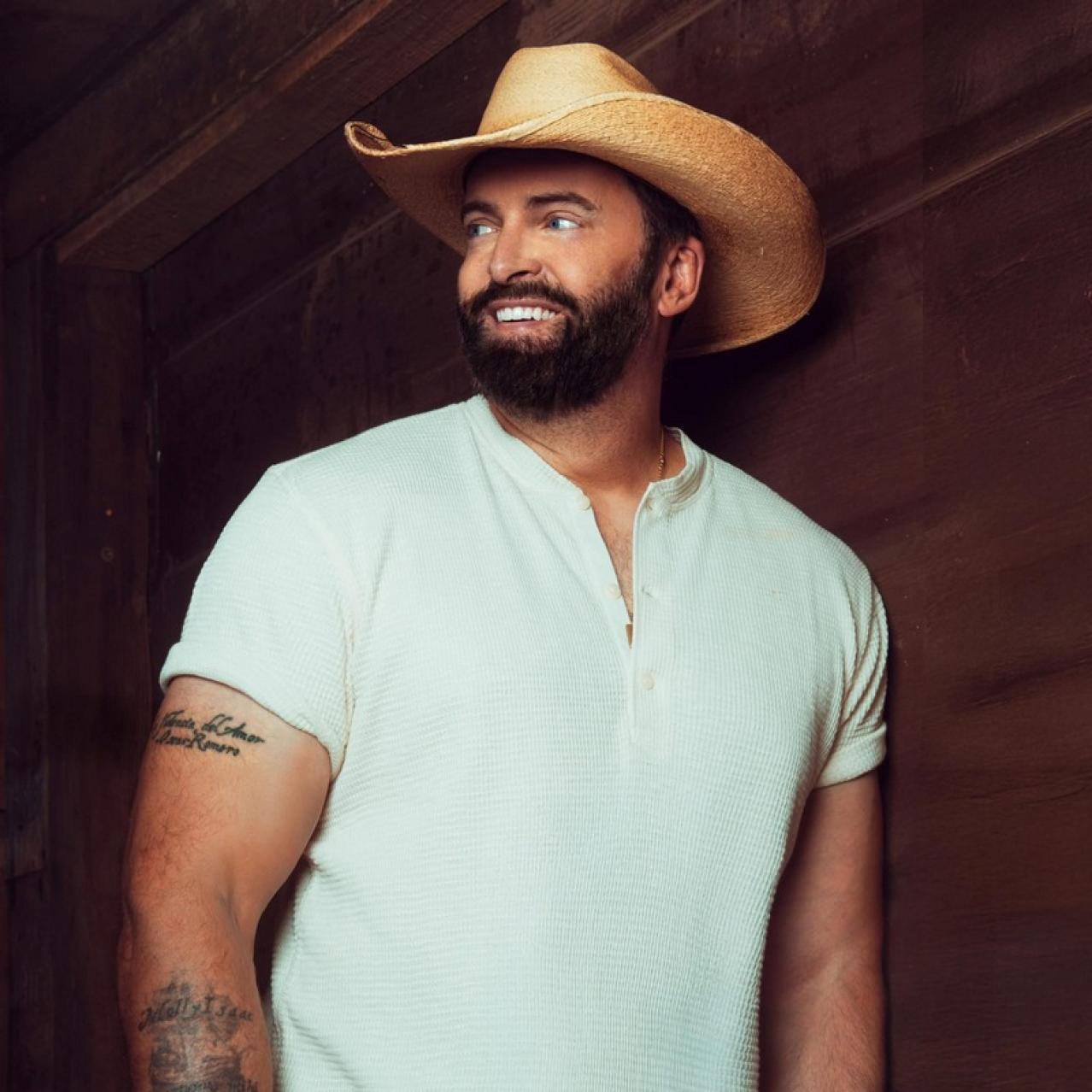 Dean Brody wearing a white shirt and a cowboy hat