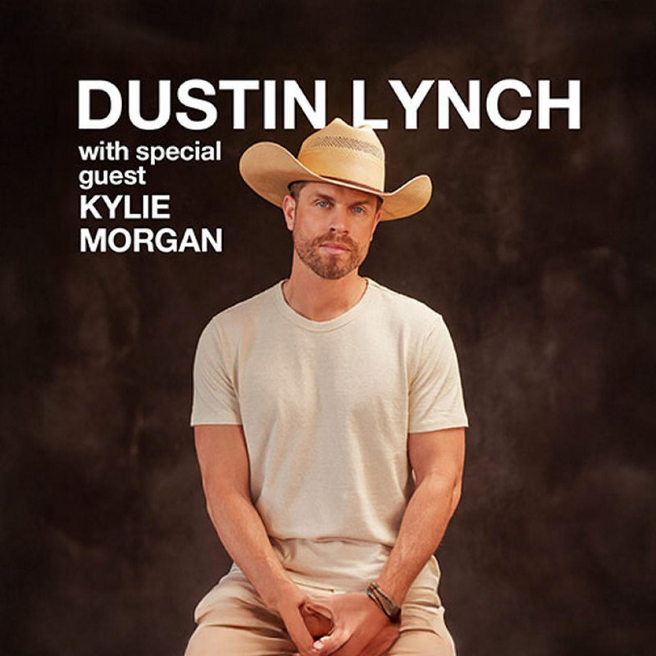 Dustin sitting down with a cowboy hat on and wearing a white t shirt