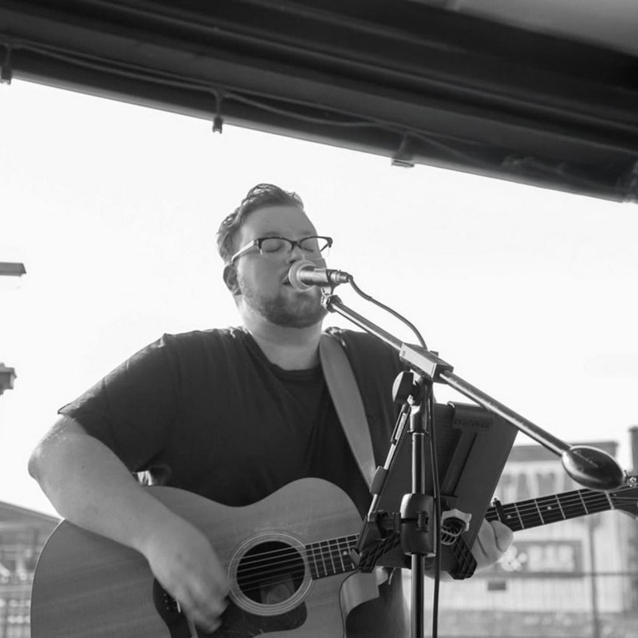 Jacob Stirpe on the patio with a guitar and microphone