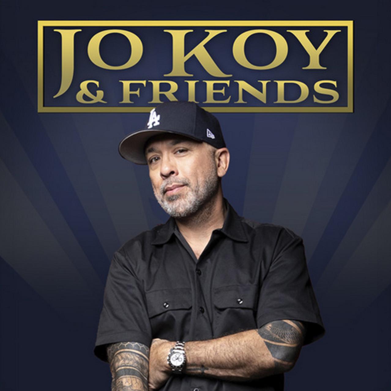 Jo Koy stands wearing a baseball hat