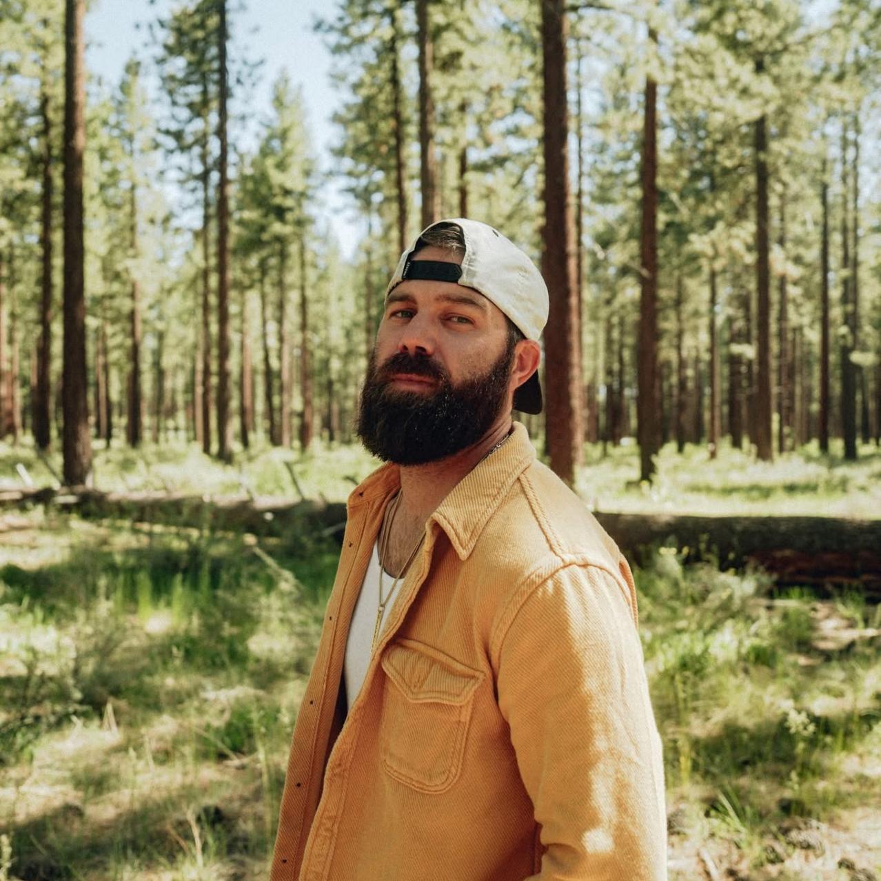 Jordan Davis stands outside surrounded by trees.
