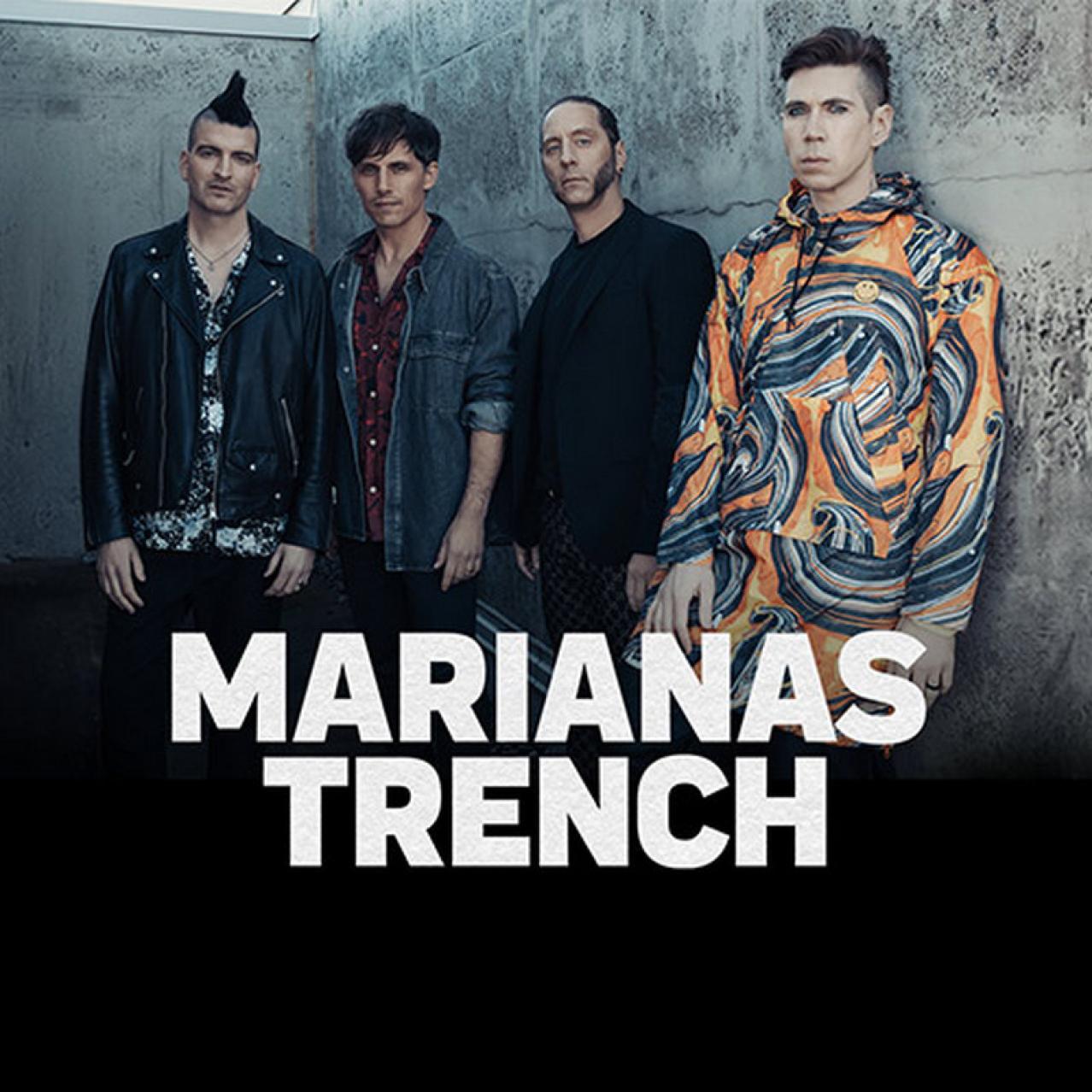 Bandmembers standing with their backs to a concrete wall
