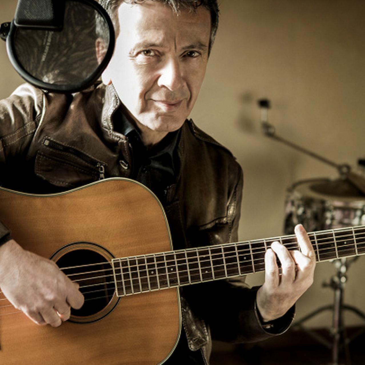 Pupo sitting with a guitar in his hand
