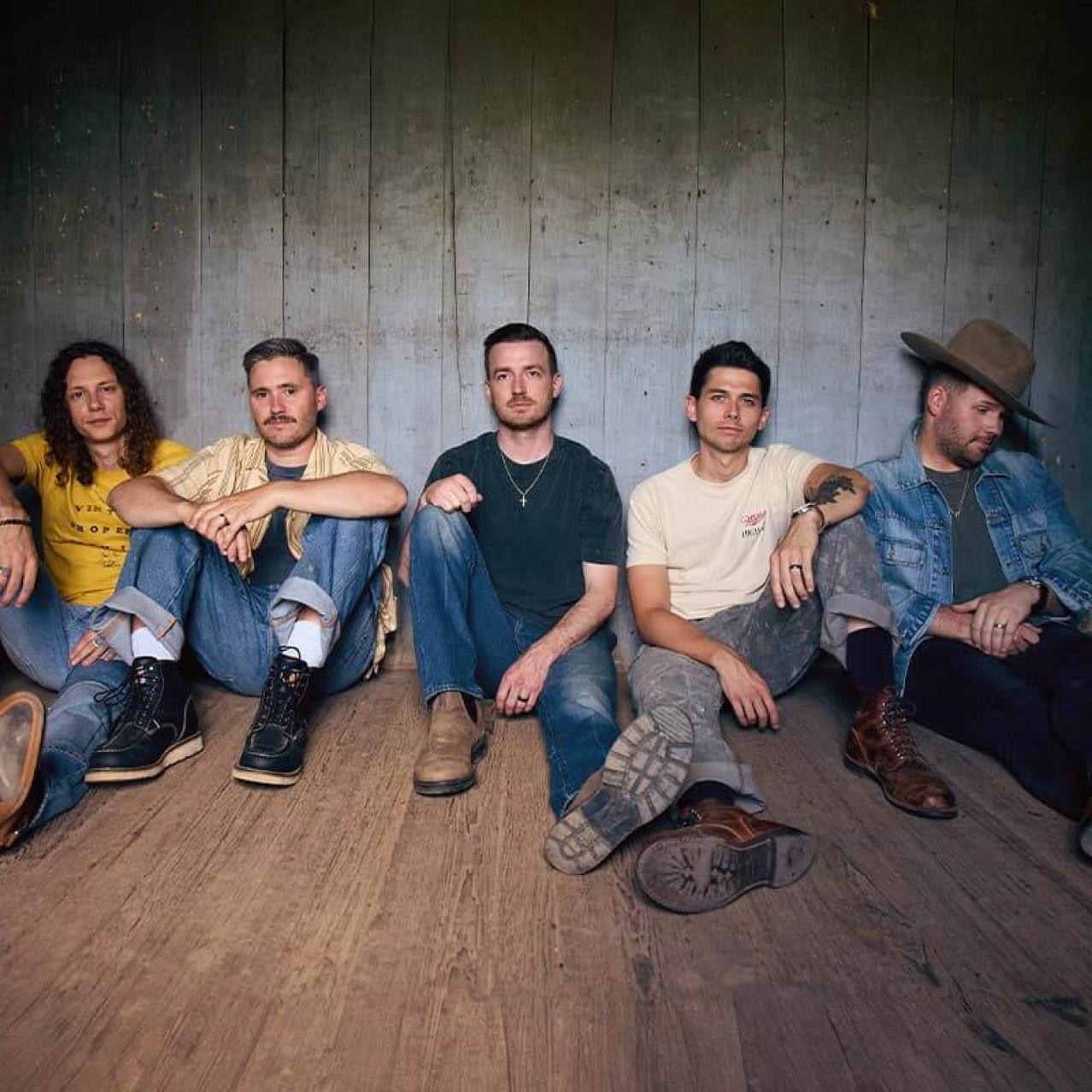 Bandmembers of LANCO sitting on a hardwood floor
