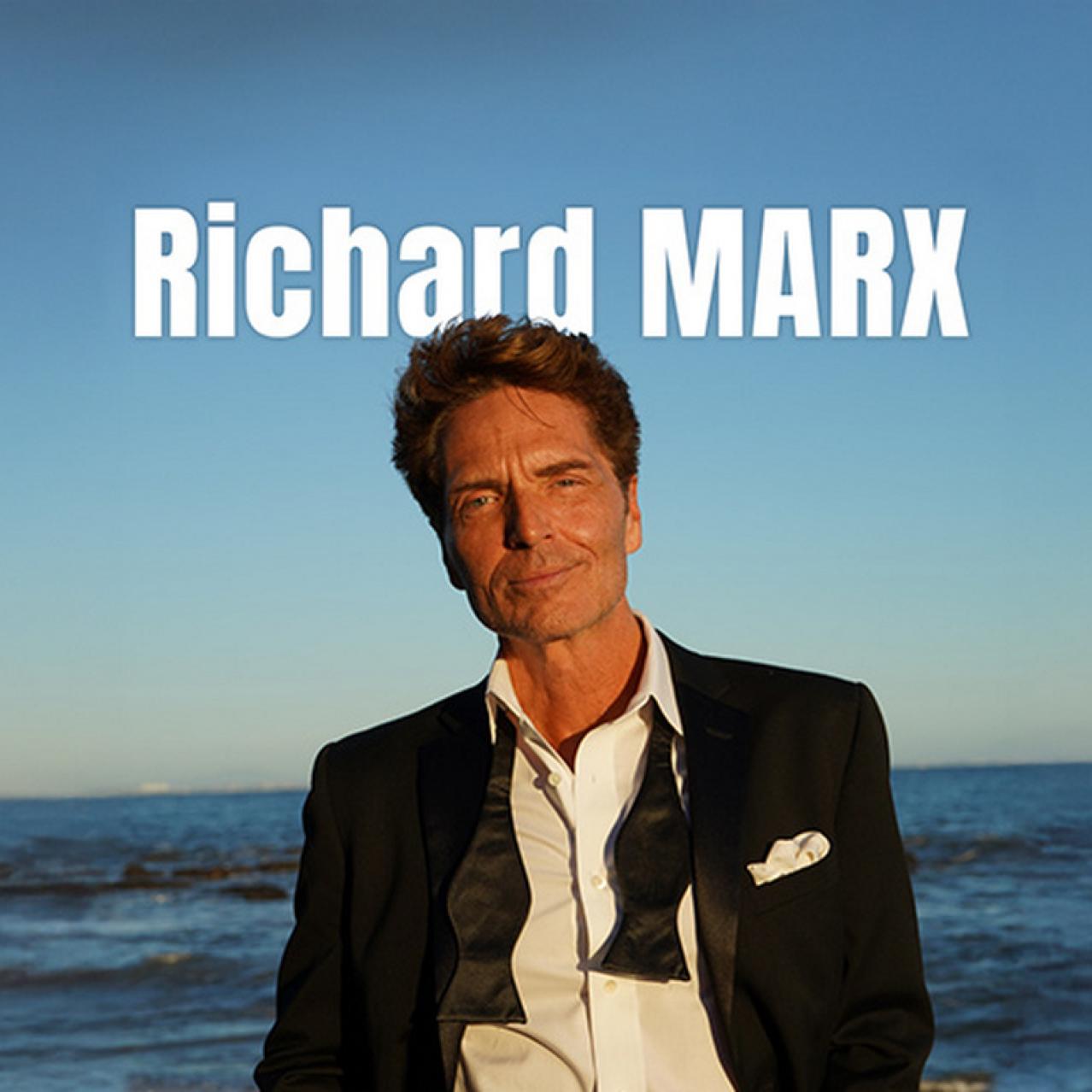 Richard Marx in a suit on a beach
