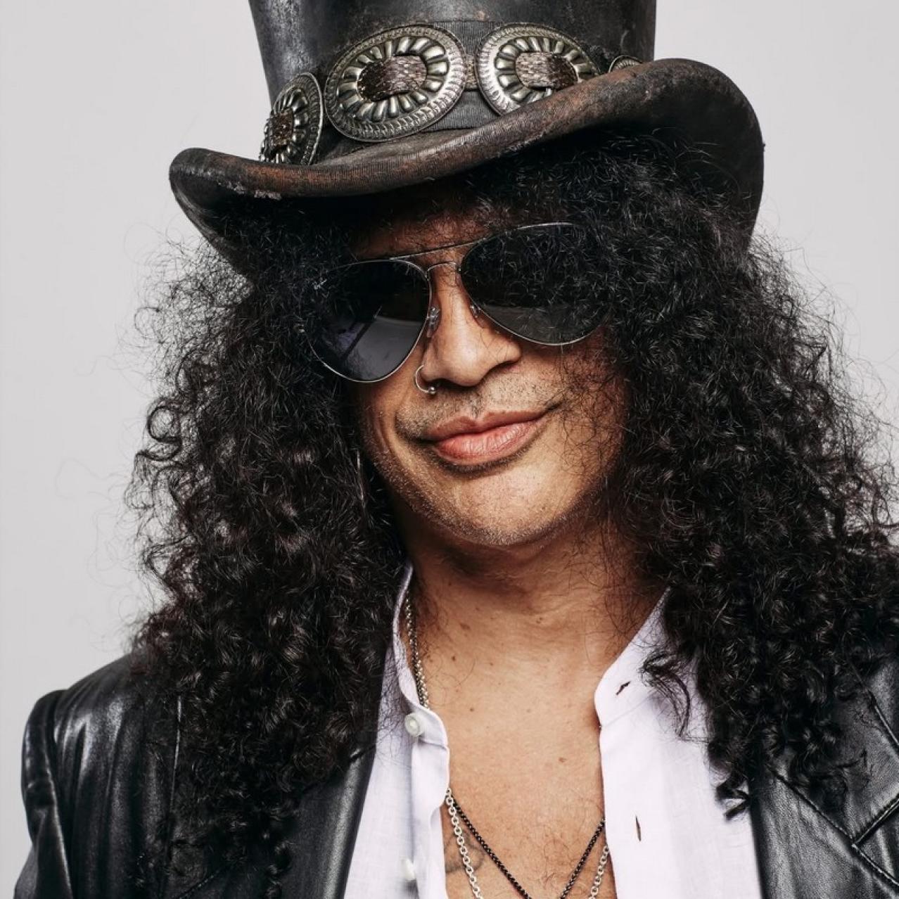 Headshot of Slash the guitarist wearing a hat and sunglasses
