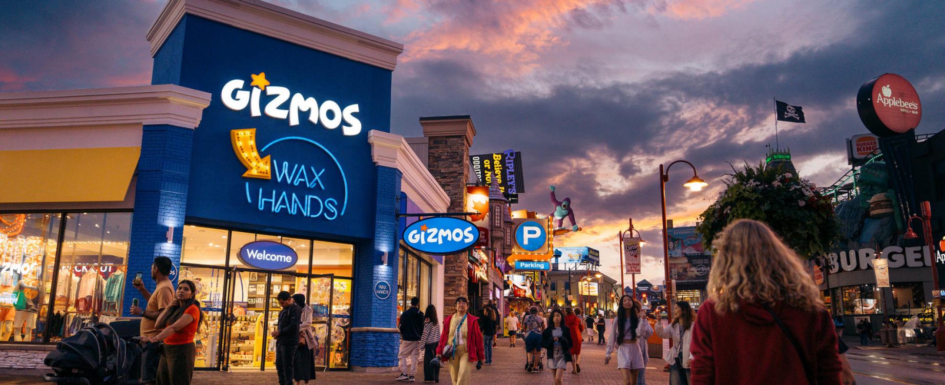 Gizmos Entrance at sunset with pedestrians walking along Clifton Hill